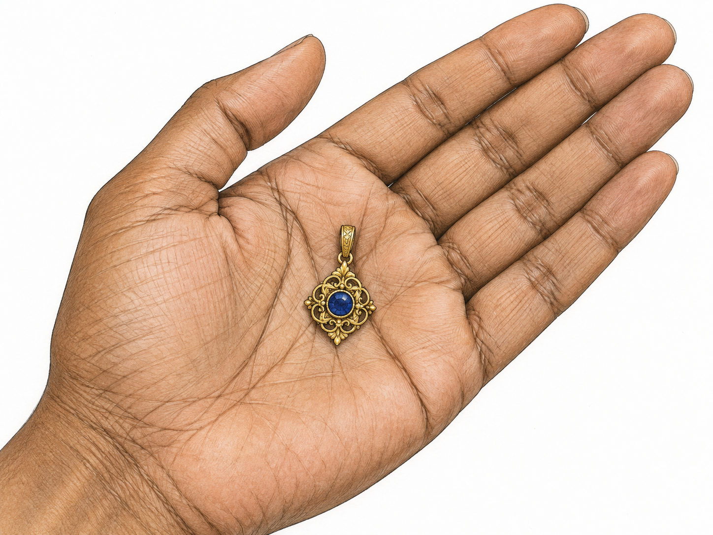 A small ornate gold pendant with a blue gem resting in an open palm.